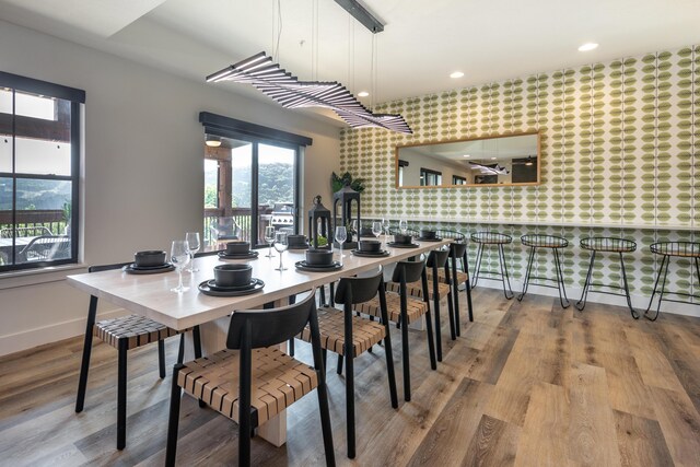 dining space with wallpapered walls, baseboards, an accent wall, wood finished floors, and recessed lighting