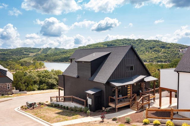 view of front of house with metal roof, a forest view, board and batten siding, and roof with shingles