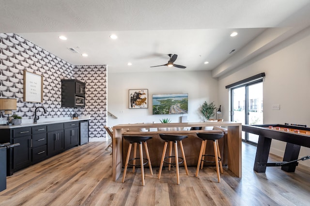 kitchen featuring light wood-type flooring, light countertops, dark cabinetry, and recessed lighting