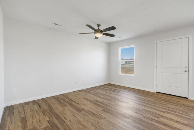 spare room featuring baseboards, visible vents, ceiling fan, and wood finished floors