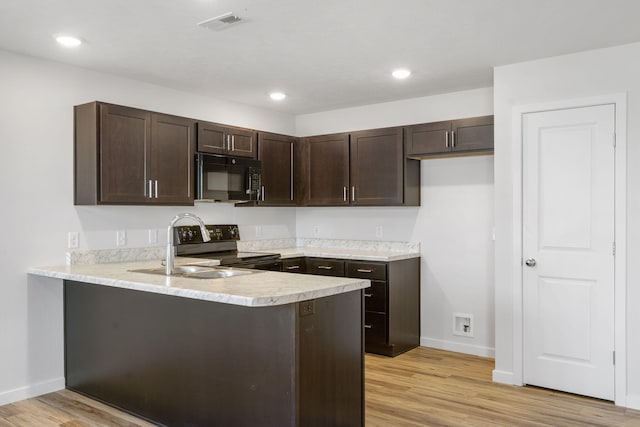 kitchen with a peninsula, black appliances, dark brown cabinetry, and light countertops