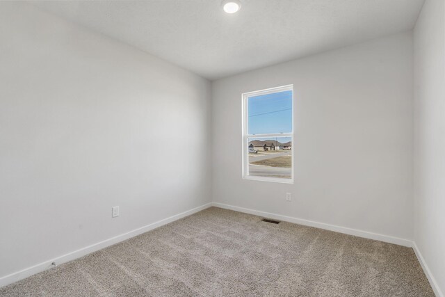 unfurnished room with carpet, visible vents, and baseboards