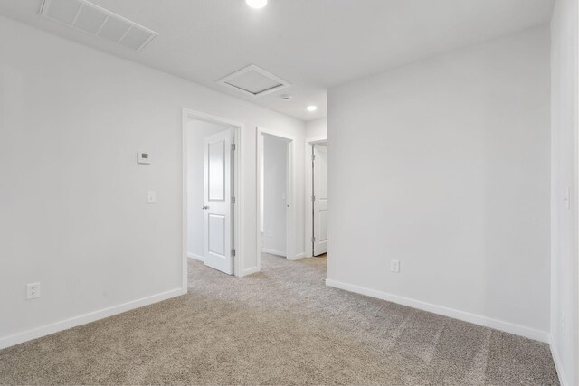 carpeted empty room featuring baseboards, recessed lighting, visible vents, and attic access