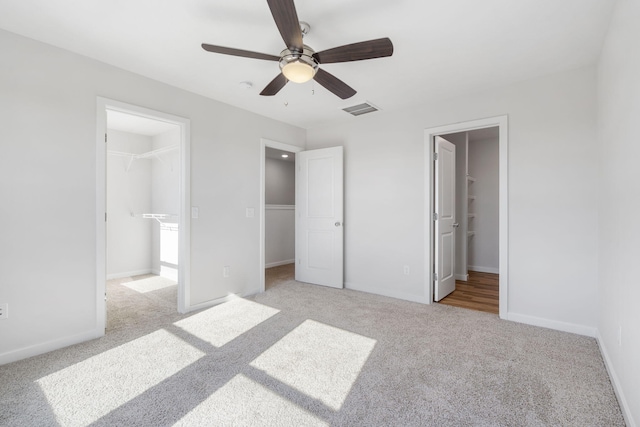 unfurnished bedroom with carpet, a closet, visible vents, a spacious closet, and baseboards