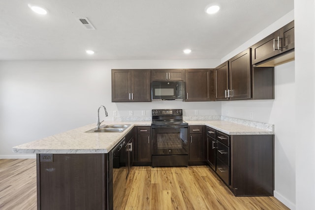 kitchen with visible vents, a sink, dark brown cabinets, a peninsula, and black appliances