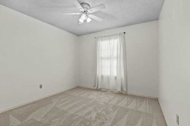 carpeted spare room with ceiling fan, baseboards, and a textured ceiling