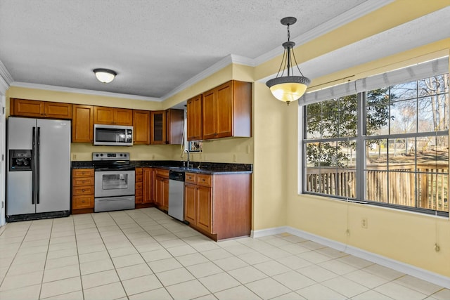 kitchen with stainless steel appliances, dark countertops, brown cabinetry, and crown molding