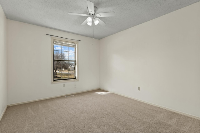 spare room with a ceiling fan, carpet, a textured ceiling, and baseboards