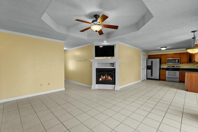 unfurnished living room with a textured ceiling, ornamental molding, a raised ceiling, and a glass covered fireplace