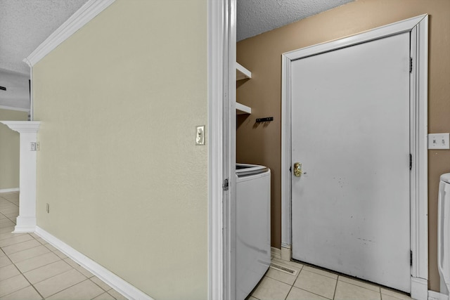 laundry area featuring light tile patterned floors, ornamental molding, a textured ceiling, washer / dryer, and laundry area