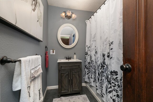 bathroom with a textured ceiling, a shower with curtain, vanity, and baseboards