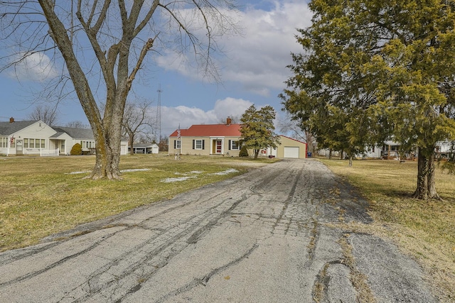 view of front facade featuring an outdoor structure, an attached garage, driveway, and a front lawn