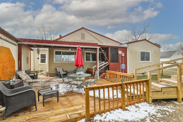 snow covered back of property with a deck