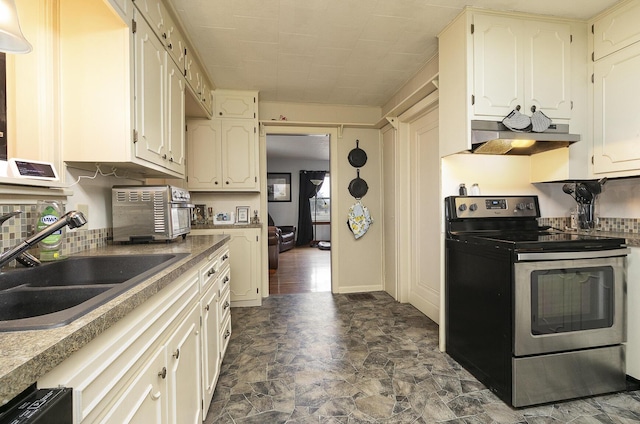 kitchen with electric range, stone finish flooring, white cabinetry, a sink, and under cabinet range hood