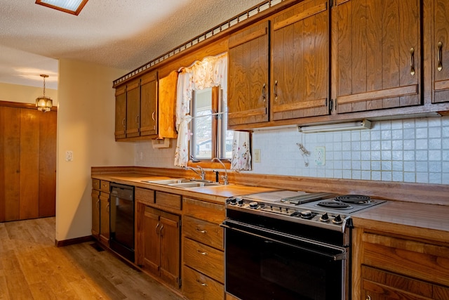 kitchen with dishwasher, electric range oven, brown cabinets, light wood-type flooring, and a sink