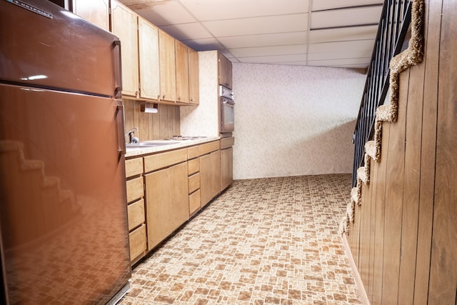 kitchen featuring freestanding refrigerator, light brown cabinets, stainless steel oven, and a paneled ceiling