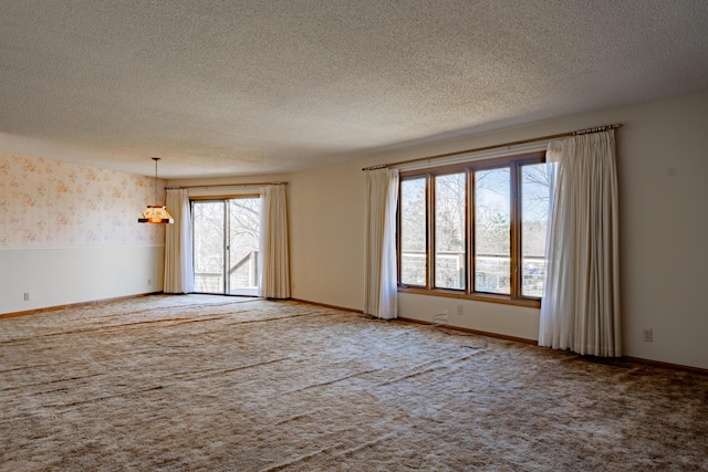 carpeted spare room with a textured ceiling, baseboards, and wallpapered walls