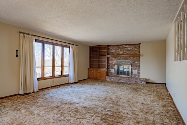 unfurnished living room with a brick fireplace, a textured ceiling, baseboards, and carpet flooring