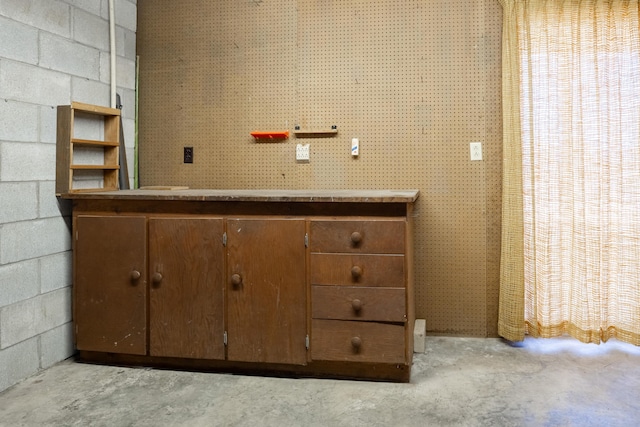 interior space featuring concrete block wall and unfinished concrete floors