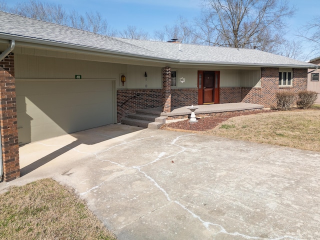 single story home featuring a shingled roof, concrete driveway, an attached garage, a porch, and brick siding