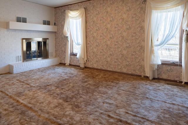 unfurnished living room featuring carpet floors, plenty of natural light, and wallpapered walls