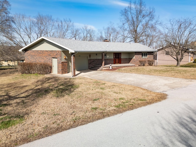 single story home with driveway, an attached garage, a front lawn, and brick siding