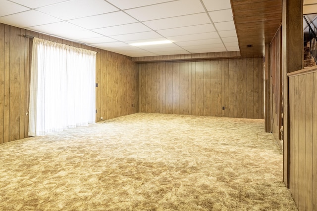 below grade area featuring carpet floors, a paneled ceiling, and wooden walls