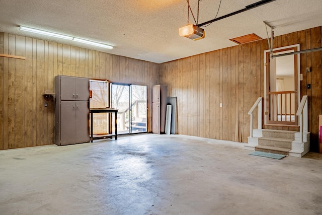 garage featuring a garage door opener and wooden walls