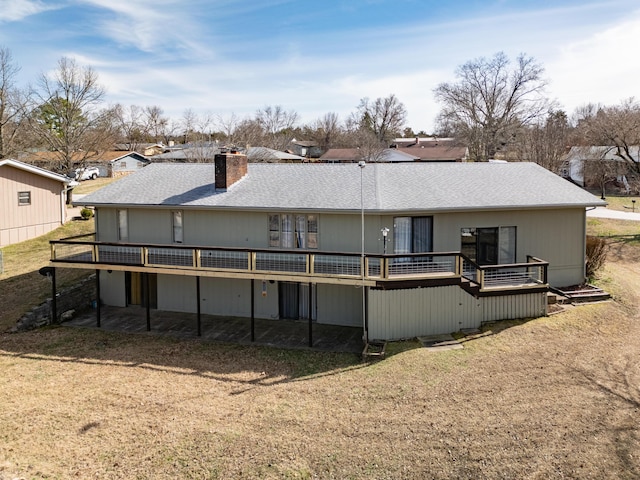 back of house featuring a deck, a shingled roof, and a chimney