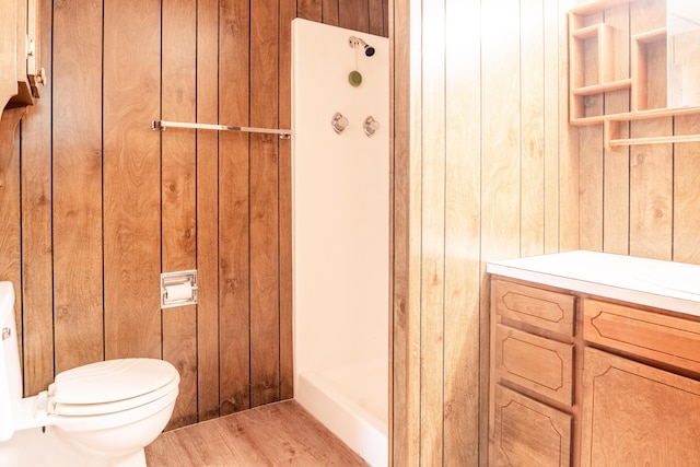 bathroom featuring toilet, wood walls, and a stall shower