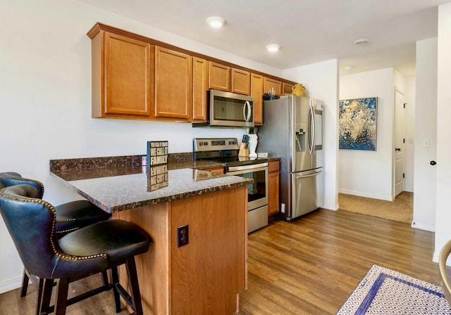 kitchen with dark wood-type flooring, brown cabinetry, and appliances with stainless steel finishes