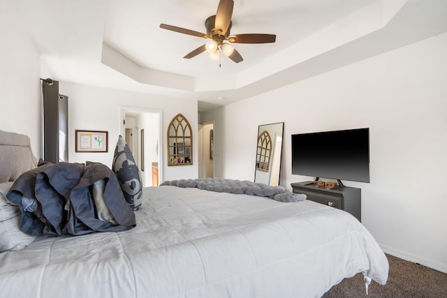 bedroom with a tray ceiling, baseboards, carpet floors, and ceiling fan