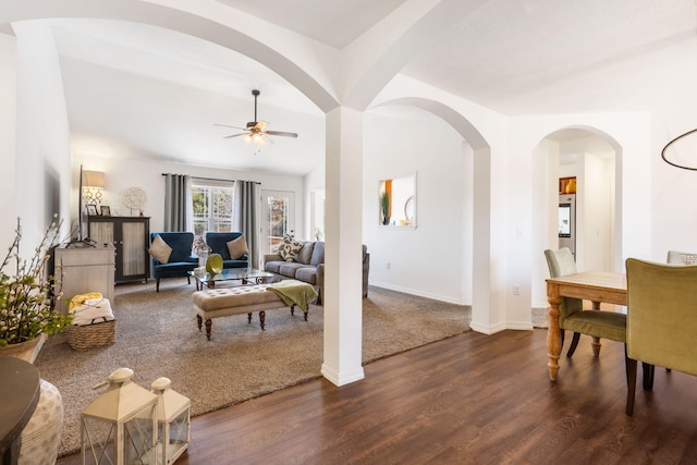 living area with ceiling fan, baseboards, and dark wood-style floors