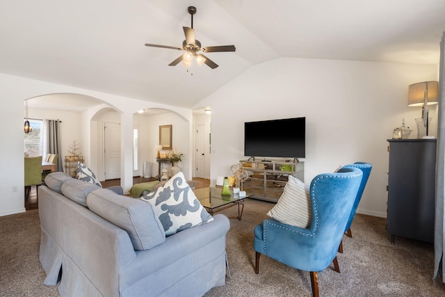 carpeted living area with baseboards, arched walkways, a ceiling fan, and vaulted ceiling