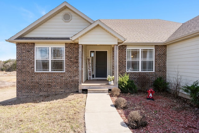 view of front of house with brick siding and a shingled roof