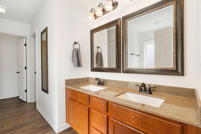 full bath featuring a sink, baseboards, wood finished floors, and double vanity