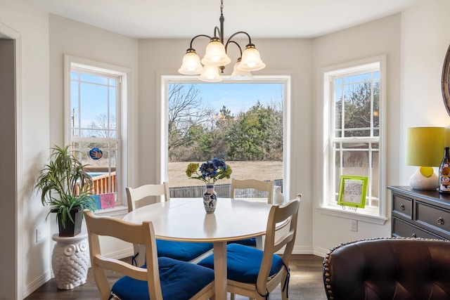 dining space featuring baseboards, an inviting chandelier, and wood finished floors