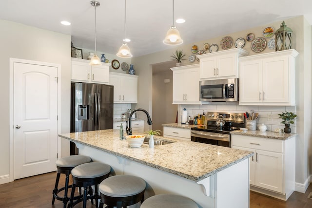 4427 E Kentbrook Dr, Springfield, MO 65802 - kitchen with appliances with stainless steel finishes, tasteful backsplash, a sink, a center island with sink, and white cabinetry