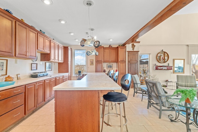 kitchen featuring light tile patterned floors, a kitchen breakfast bar, decorative light fixtures, a center island, and light countertops