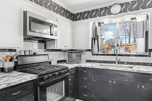 kitchen featuring black gas range oven, a sink, stainless steel microwave, and dark cabinetry