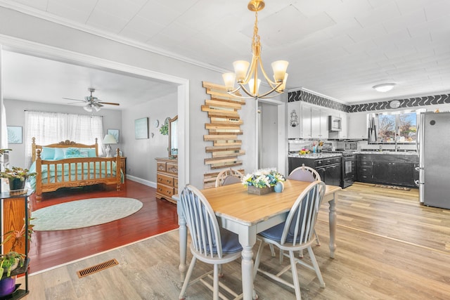 dining room featuring light wood-style floors, baseboards, visible vents, and a wealth of natural light