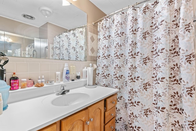 full bathroom featuring tasteful backsplash, visible vents, a shower with curtain, vanity, and tile walls