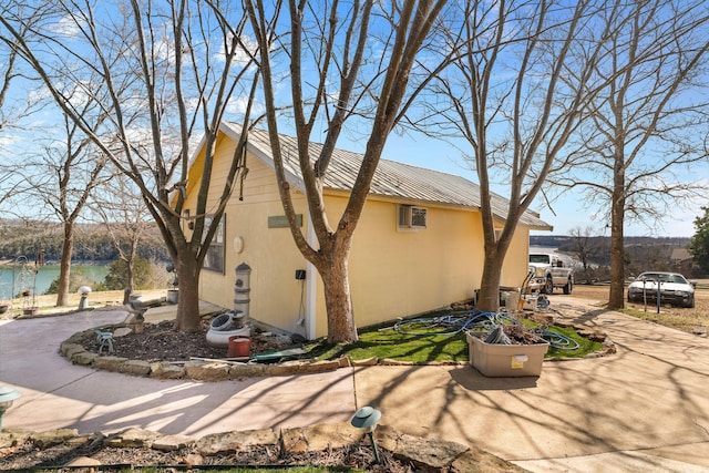 view of home's exterior featuring a water view, metal roof, and stucco siding