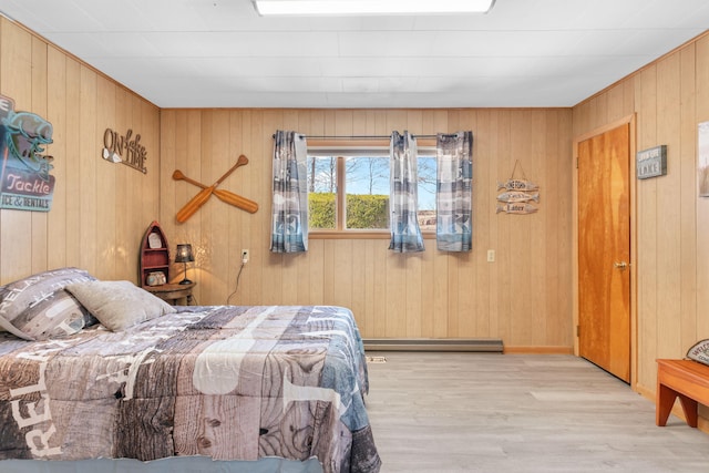 bedroom with baseboard heating and wood finished floors