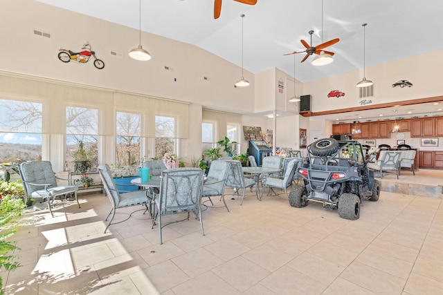 interior space with a healthy amount of sunlight, high vaulted ceiling, ceiling fan, and visible vents