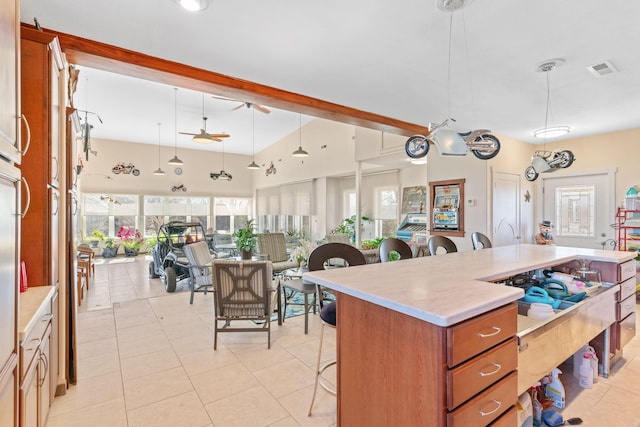 kitchen with visible vents, a kitchen breakfast bar, open floor plan, light countertops, and brown cabinets