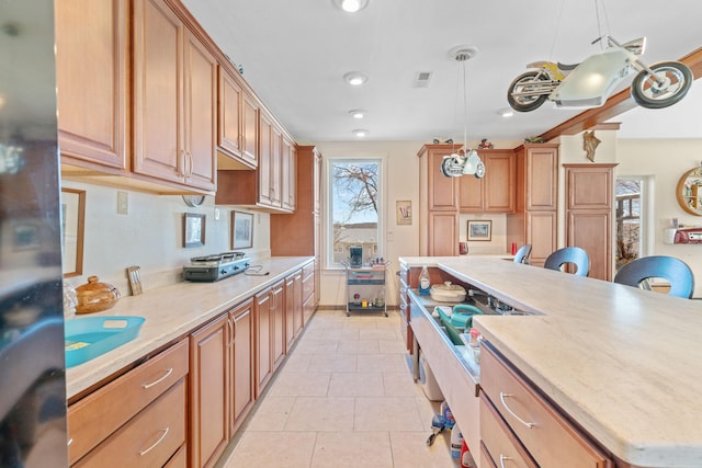 kitchen featuring stainless steel fridge, visible vents, a kitchen island, decorative light fixtures, and light tile patterned flooring