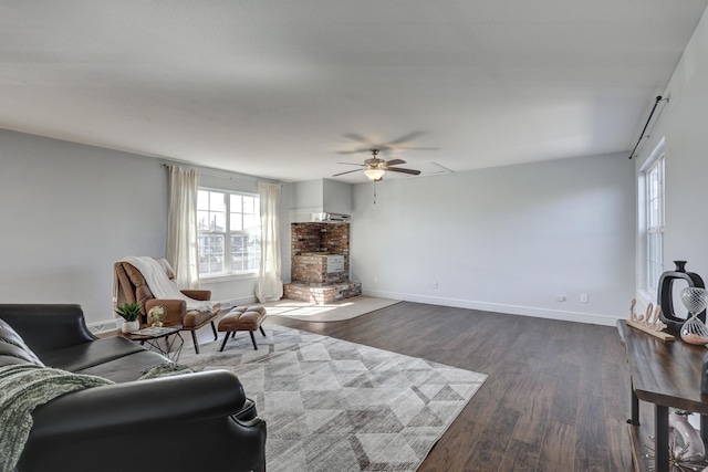 living area with a ceiling fan, baseboards, and dark wood-type flooring