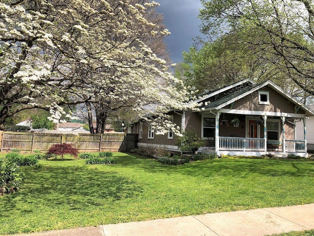 view of front of property featuring fence, a porch, and a front yard