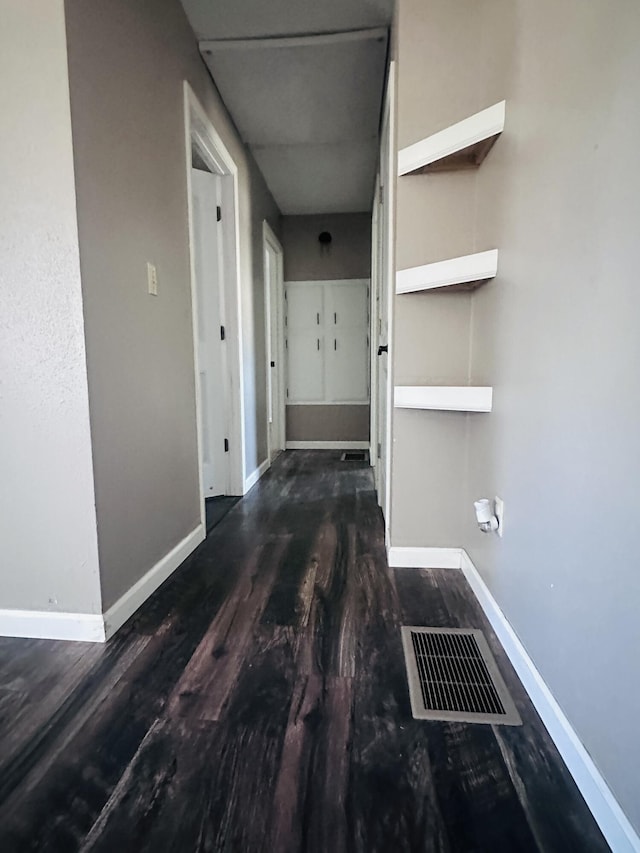 corridor featuring visible vents, baseboards, and wood finished floors